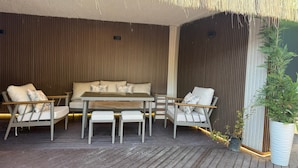 An outdoor seating area with a sofa and chairs, a table, and a potted plant.