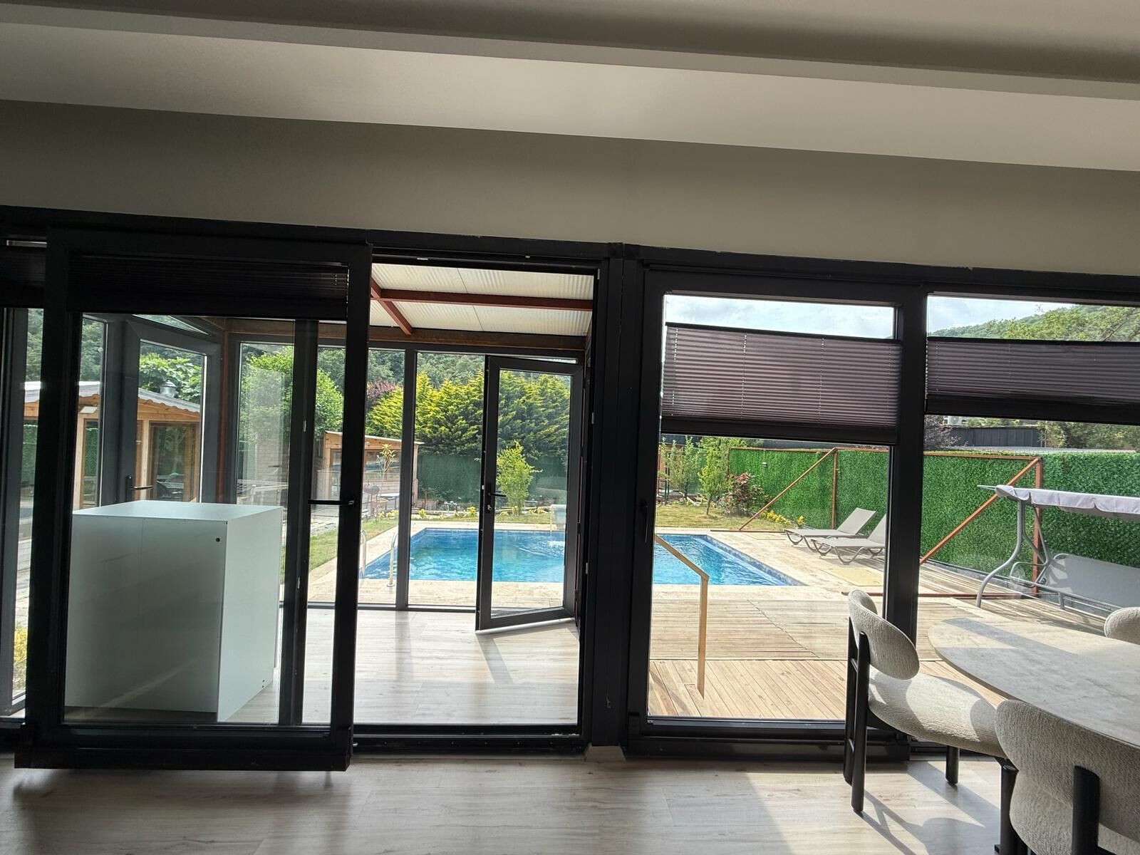 Un interior moderno con amplios ventanales correderos que dan a una zona de piscina exterior.