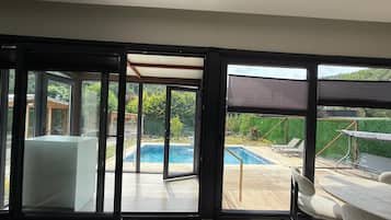 Un interior moderno con amplios ventanales correderos que dan a una zona de piscina exterior.
