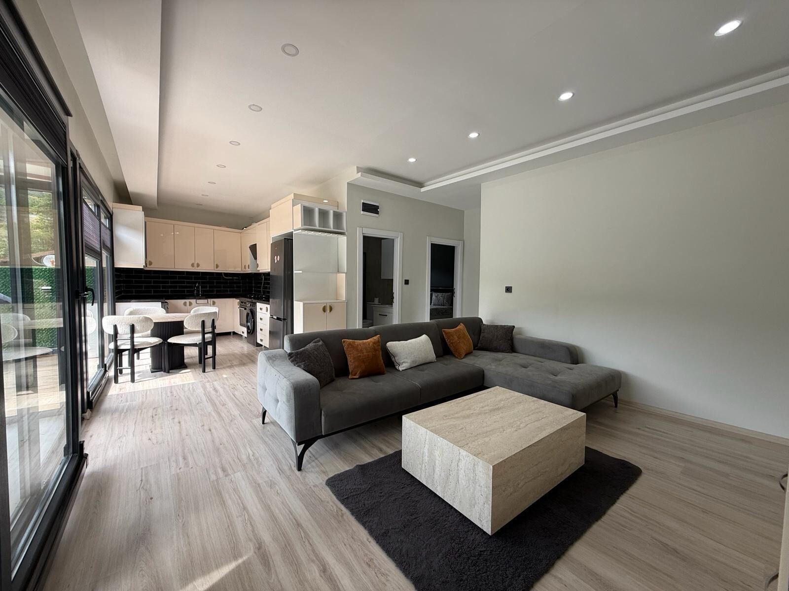 A modern living room with a grey sofa, a coffee table, and a kitchen in the background.