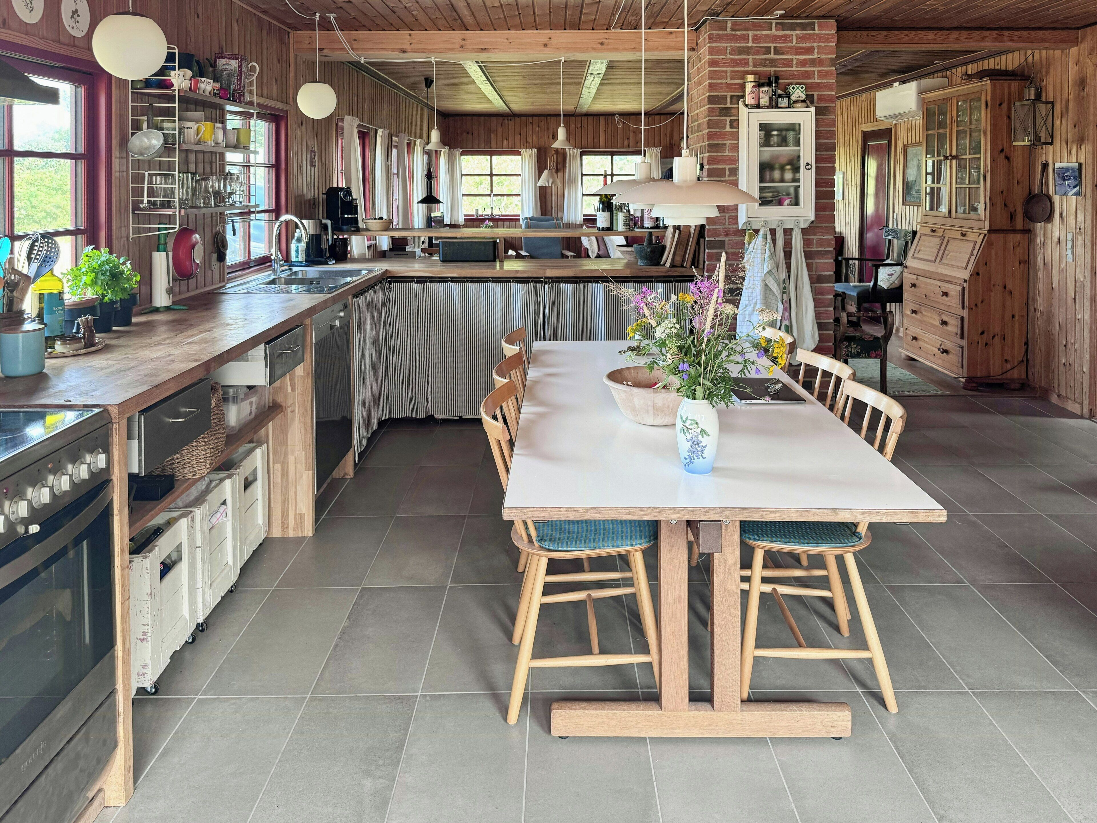 A spacious kitchen with a large island, wooden cabinets, and a dining area with chairs.