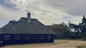 Un edificio con una chimenea, varias ventanas y un campo verde al frente.