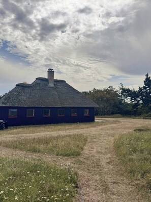 Ein Gebäude mit Schornstein, einer Reihe von Fenstern und einem grünen Feld im Vordergrund.