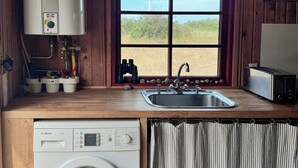 Una cocina compacta con lavadora Bosch, un lavabo y una ventana con vistas al exterior.