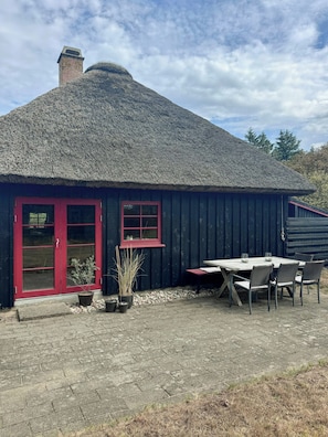 A building with a thatched roof, a red door, and a small window. - Thatched holiday home on the Limfjord's edge (Spoettrup)