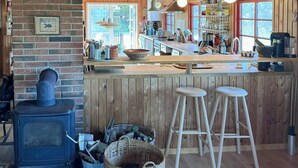 Una cocina rústica con pared de ladrillo, techo de madera y un ventanal grande.
