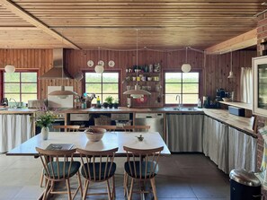 A kitchen with wooden paneling, a central island with chairs, a sink, and various kitchen appliances.