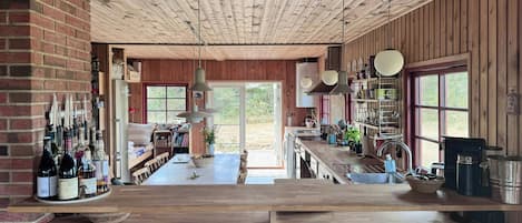 A rustic kitchen with wooden beams, a central island with stools, and a brick wall.