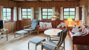 Una habitación acogedora con paredes de madera, un sofá de cuero, una mesa de madera y un televisor sobre un mueble de madera.