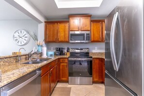 Eine Küche mit Holzschränken, einem Edelstahlkühlschrank, einer Mikrowelle, einem Backofen und einem Spülbecken.