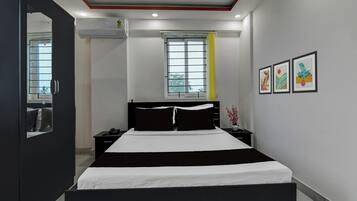 A modern bedroom with a bed, bedside tables, a mirror, and artwork on the wall.