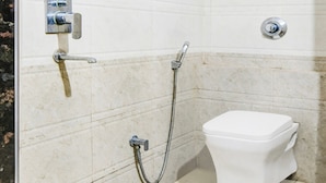 A bathroom with a shower, toilet, and a wall-mounted faucet.