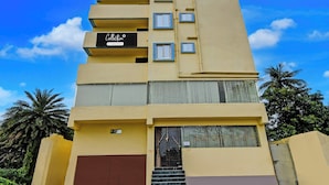 A multi-story hotel with a flat facade, balconies, and a ground entrance with a staircase.