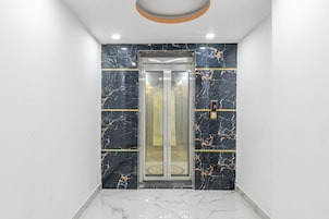 Un ascensor con puerta de vidrio, paredes de mármol y un panel digital que muestra el número 3.