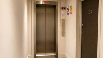A hallway with an elevator, a door marked with the number 38, and a fire alarm on the wall.