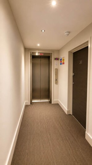 A hallway with an elevator, a door marked with the number 38, and a fire alarm on the wall. - Watford Central 1BR | Sleeps 4 | Near Harry Potter (Watford)