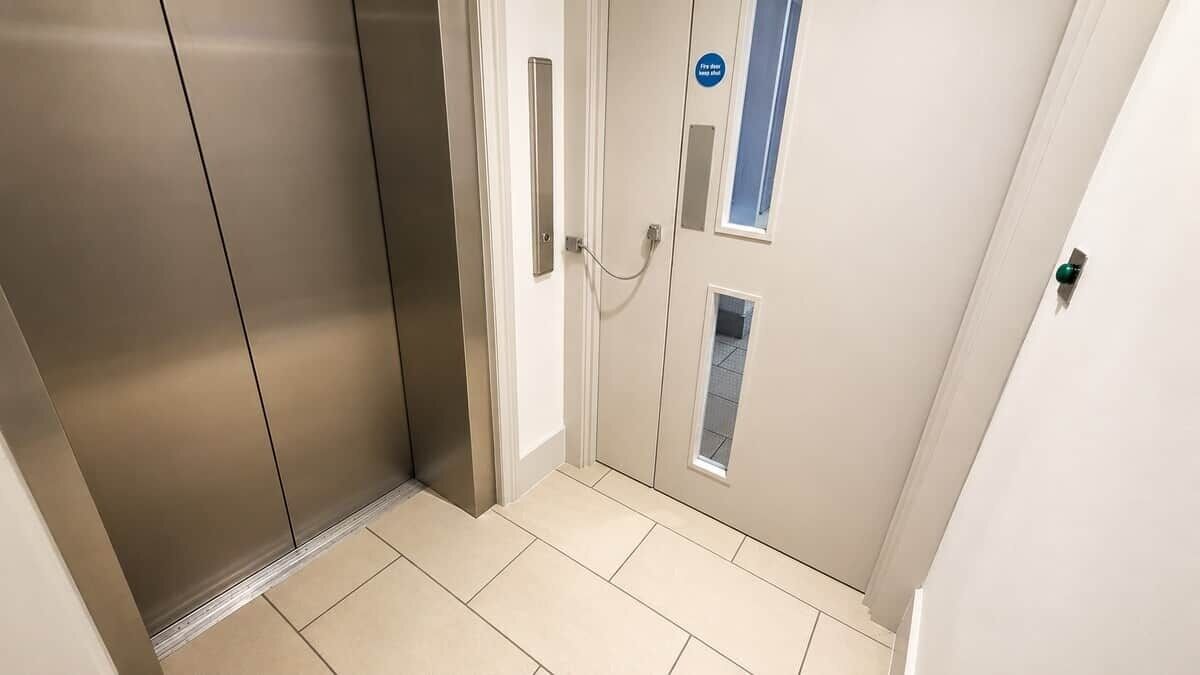 A corridor with a door, a small window, and a doorbell.