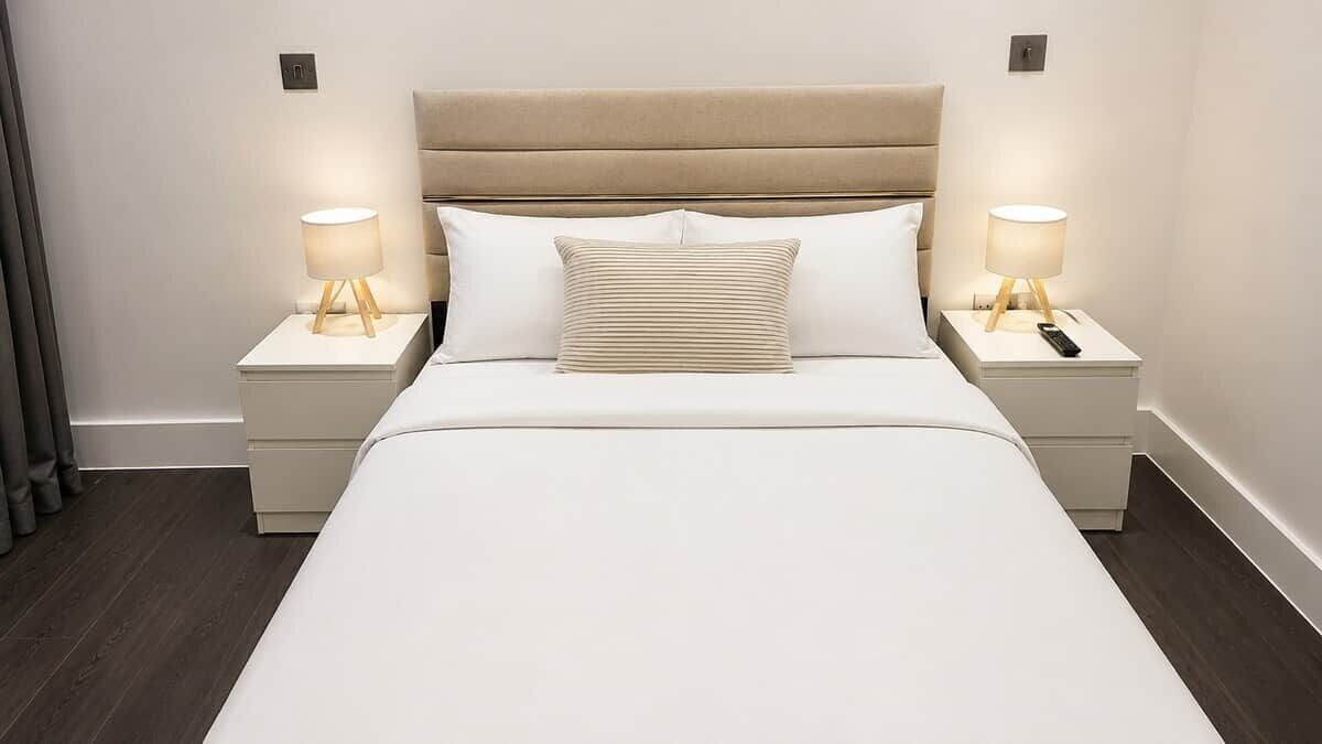 A hotel room with a bed, two bedside tables, and lamps.