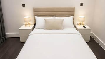 A hotel room with a bed, two bedside tables, and lamps.