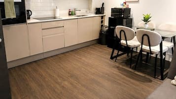 A modern kitchen with a dining area, wooden flooring, and a small table with chairs.