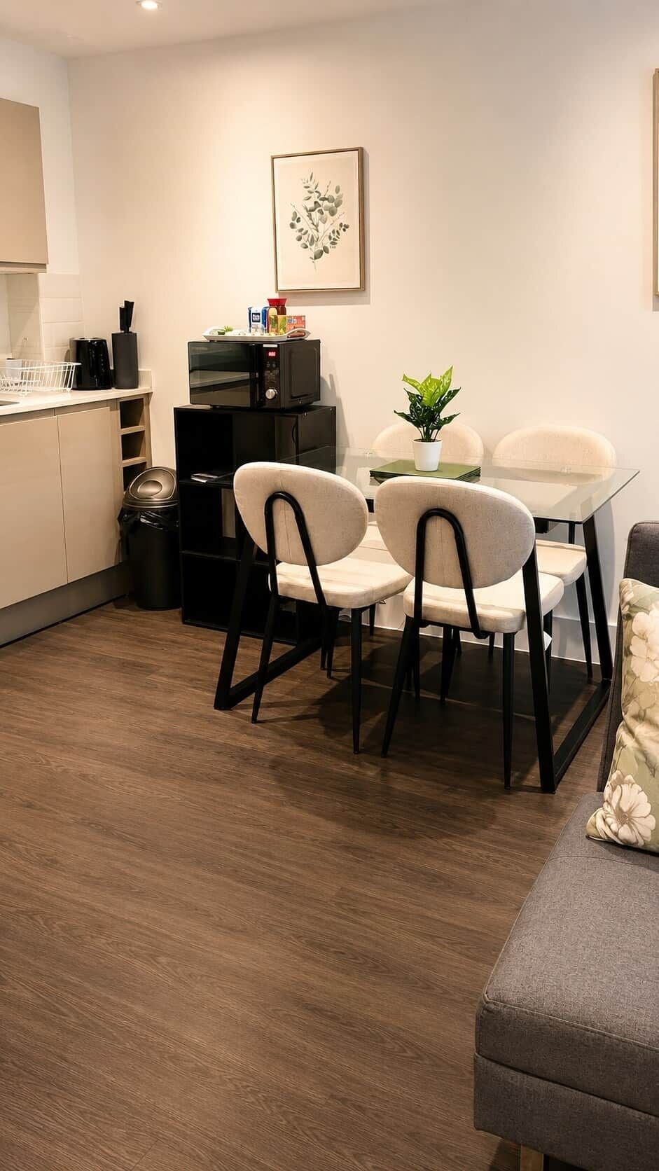 A compact living space with a kitchenette, a dining table with chairs, and a small sofa.