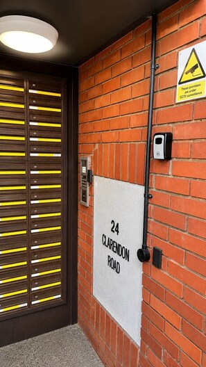 Una puerta con paneles de números de habitación, una señal de calle y un cartel de advertencia de circuito cerrado de televisión.
