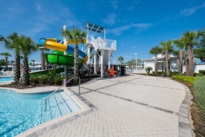 Ein Poolbereich mit Wasserrutsche und Rettungsschwimmturm.