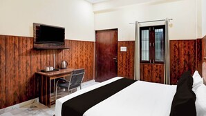 Ein Hotelzimmer mit einem Bett, einem Schreibtisch, einem Stuhl, einem Fernseher und einem Fenster mit Gitterstäben.