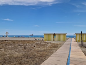 Ein Strand mit einem Rettungsturm, Strandkörben und einer Holzpromenade.