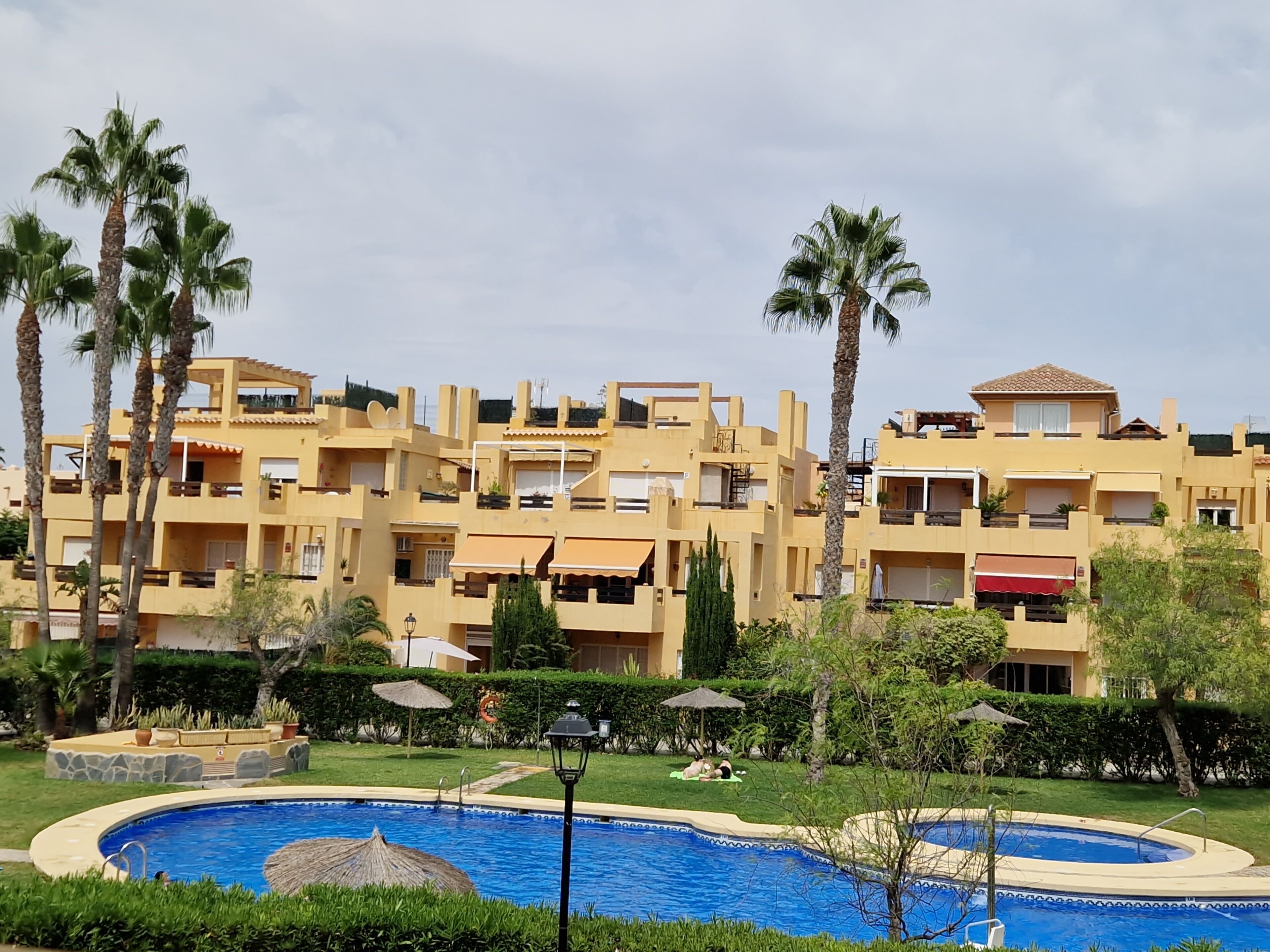 Un edificio residencial con varios balcones, piscina y palmeras.