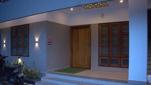 A modern building entrance with a reception sign, a wooden door, and a motorcycle parked outside. - Pop Tavern Nakshatra Apartments  (Thiruvananthapuram)