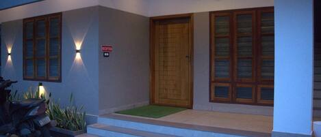 A modern building entrance with a reception sign, a wooden door, and a motorcycle parked outside.