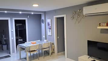 Un espace de vie compact comprenant un coin repas, un téléviseur et une petite cuisine.