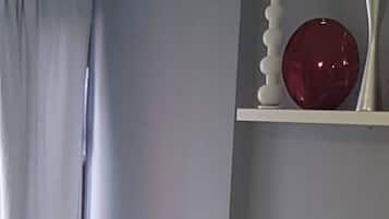 Un salon moderne avec un canapé gris, un fauteuil foncé et un objet décoratif rouge posé sur une étagère.