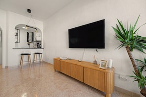 Ein modernes Wohnzimmer mit einem wandmontierten Flachbildfernseher, einem Holzkonsole und einem Topf mit Pflanze.
