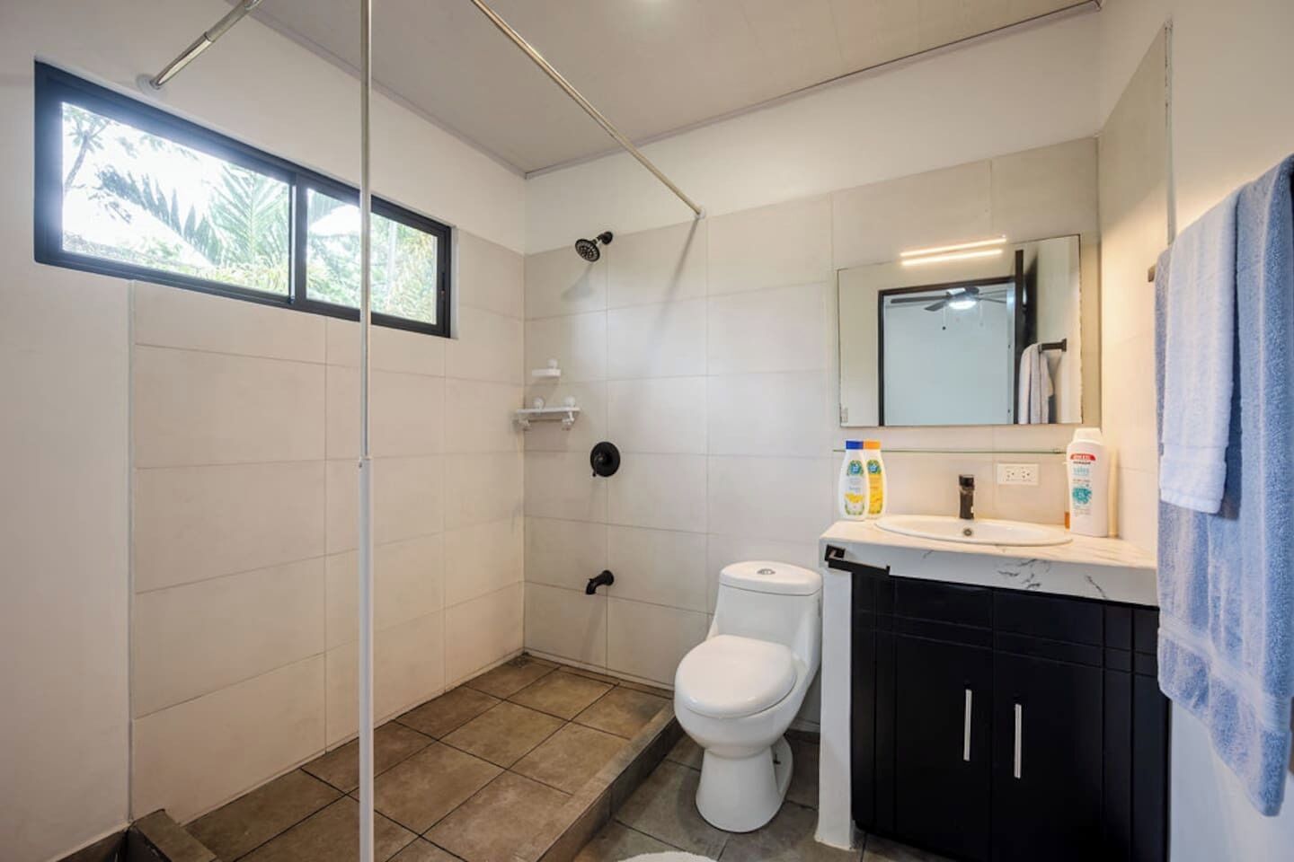 A bathroom with a shower, toilet, and sink.