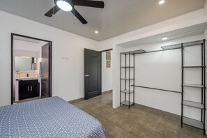 A bedroom with a bed, a wardrobe, a ceiling fan, and a bathroom with a mirror and sink. - Buena Vista Escape | Lake Views, Pool & Nature (Tilarán)