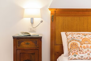 Une table de chevet en bois, avec une lampe, un livre et un panneau décoratif.