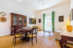 Un coin repas avec une table en bois dressée pour quatre personnes, entourée de chaises. Un meuble avec des portes en verre est adossé au mur, et un tableau est accroché au-dessus.
