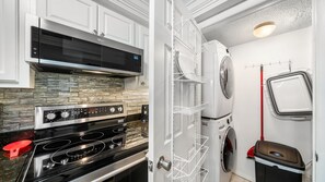 Eine kompakte Küche mit einem Edelstahlherd, einer Mikrowelle und einem eingebauten Backofen. Es gibt einen Waschbereich mit einer Waschmaschine und einem Trockner.