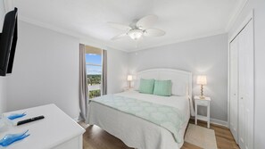 Ein Schlafzimmer mit einem Bett, Nachttischen, einem Deckenventilator und Blick ins Freie.