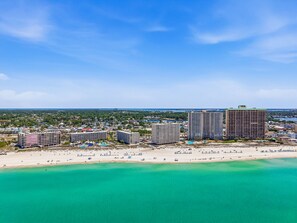 Een kuststadsgezicht met hoge gebouwen, een strand en helder turquoise water.