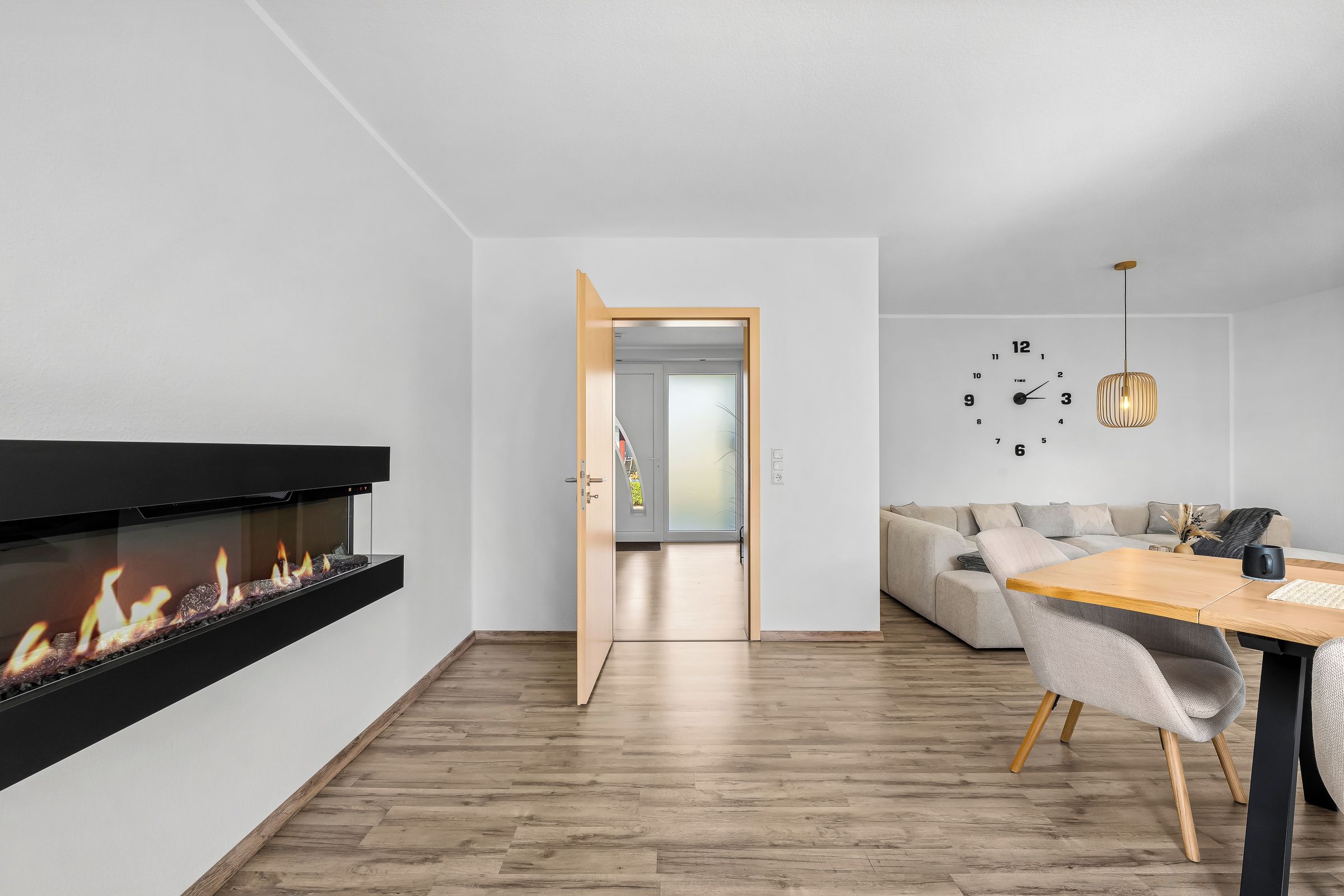A modern living room with a fireplace, a dining area, and a sofa.