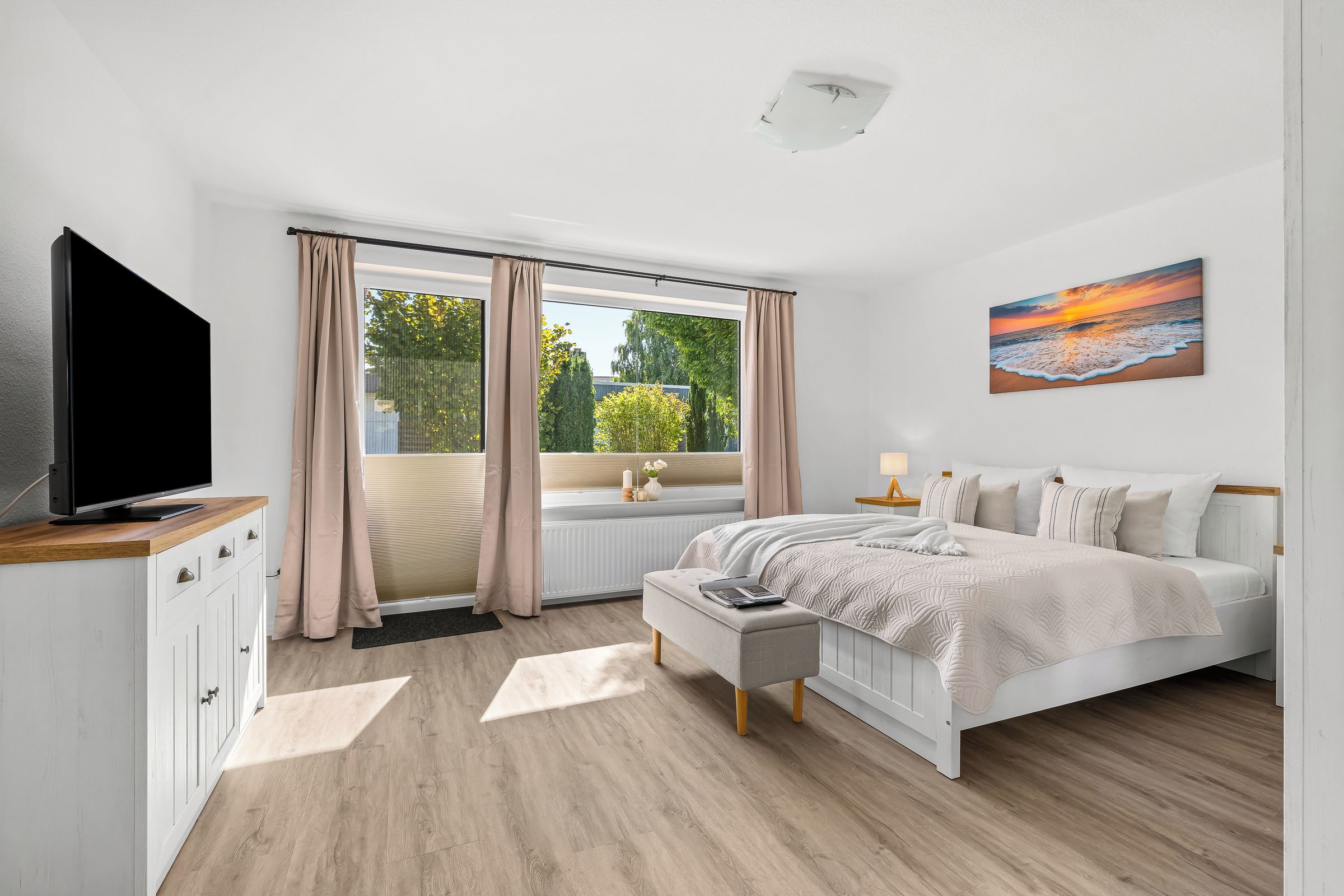 A modern bedroom with a bed, a TV, and a painting.