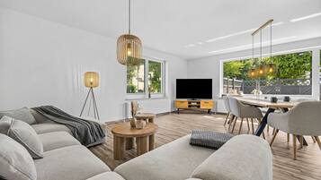 A modern living room with a sofa, coffee table, and dining area.