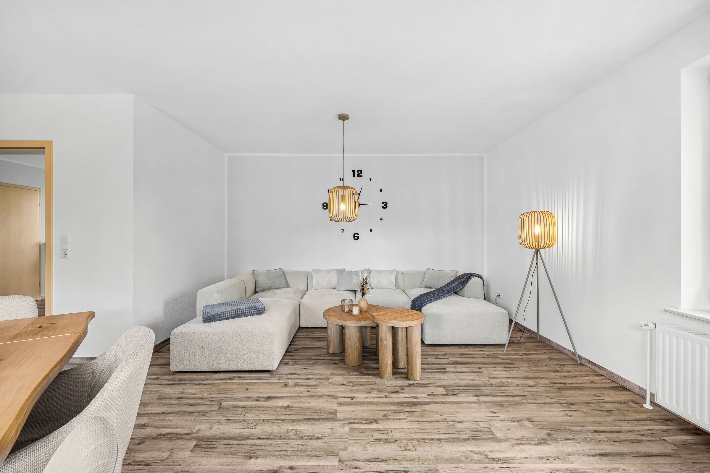 Ein modernes Wohnzimmer mit einem Ecksofa, einem Holztisch und zwei Pendelleuchten.