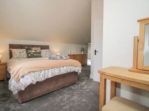 Un dormitorio con una cama, mesitas de noche, un aparador de madera y un espejo.