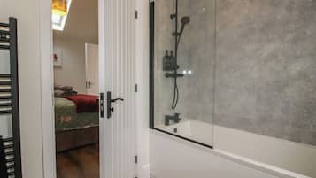 Un baño moderno con cabina de ducha de vidrio, ducha visible y bañera.