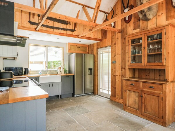 A kitchen with wooden cabinets, a refrigerator, and a window. - Little Orchard (Salisbury)