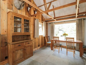A wooden interior with a dining area, stone flooring, and a window with curtains. - Little Orchard (Salisbury)